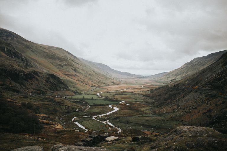 Breathtaking view of a mountain valley with a winding river, enveloped by foggy hillsides.