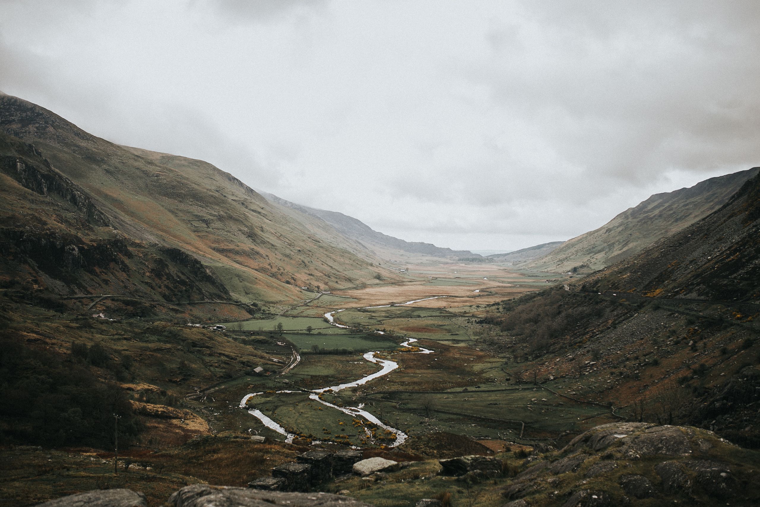 Breathtaking view of a mountain valley with a winding river, enveloped by foggy hillsides.