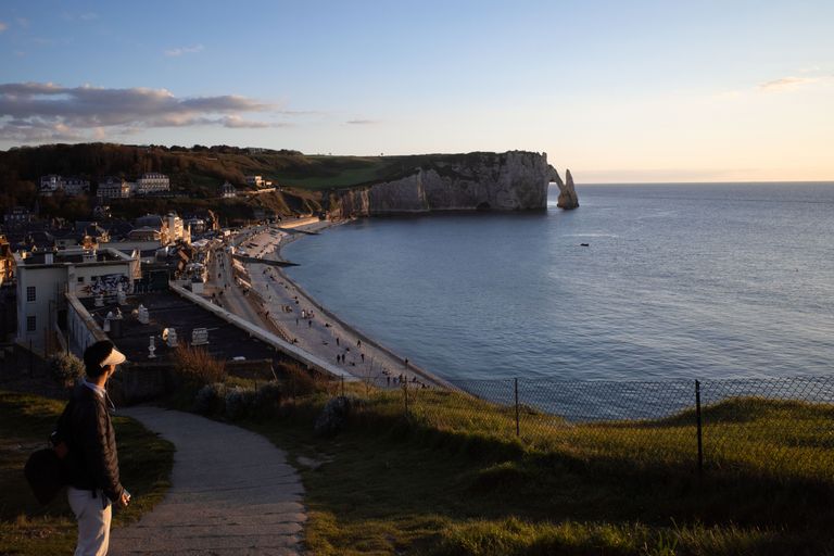 Breathtaking view of Etretat cliffs overlooking the beach and town at sunset in Normandy, France.